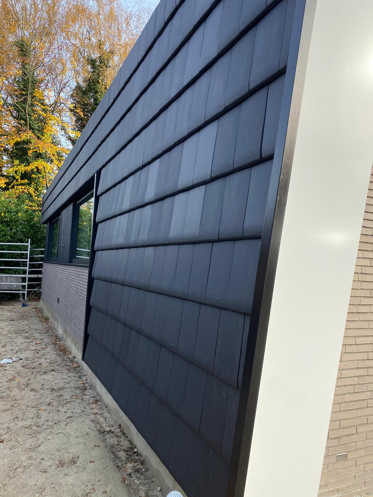 Detail van de moderne gevelafwerking van een nieuwbouw woning aan de Goorsestraat in Hengevelde met donkere dakbekleding, wit zetwerk en strakke afwerking.