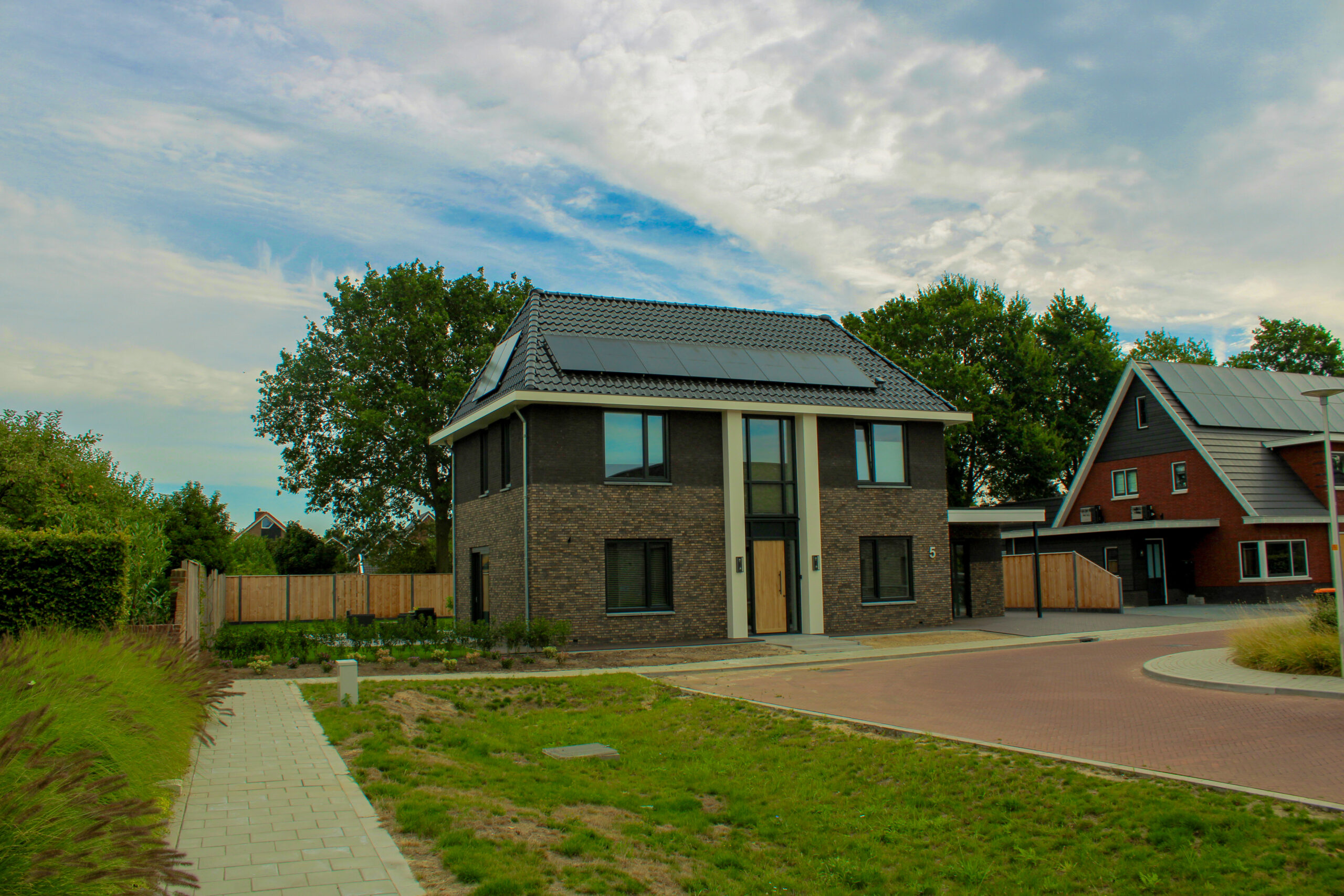 Vrijstaande nieuwbouwwoning met donkere bakstenen gevel, schilddak en zonnepanelen in Hengevelde