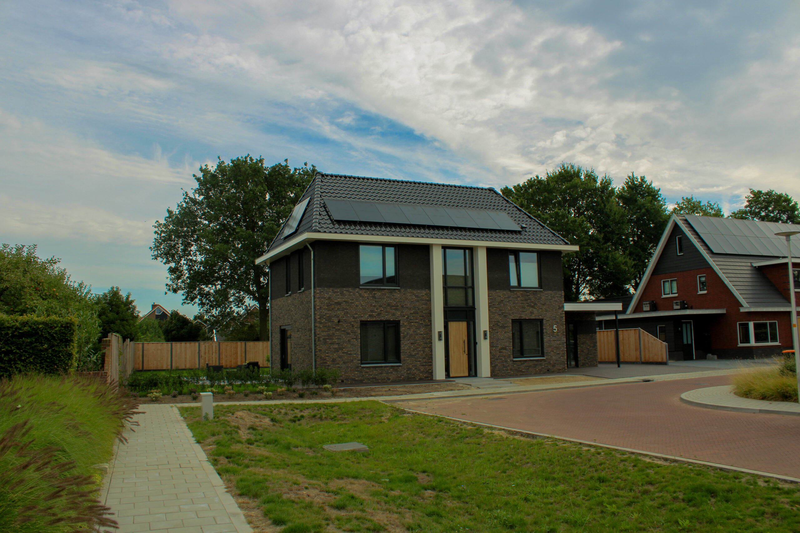 Vrijstaande nieuwbouwwoning met donkere bakstenen gevel, schilddak en zonnepanelen in Hengevelde