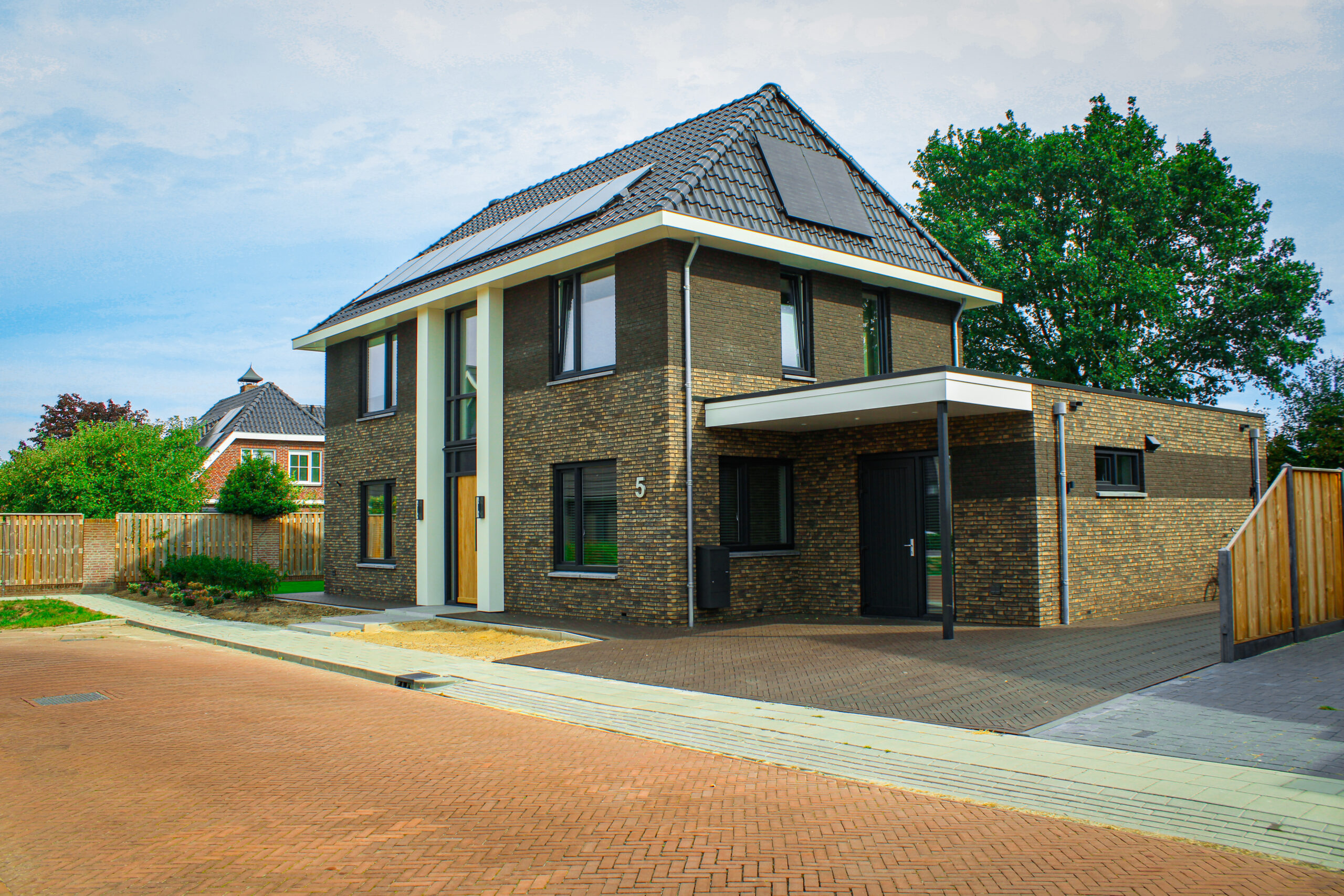 Voorzijde van vrijstaande nieuwbouwwoning De Marke 3 met donkere bakstenen gevel en houten voordeur
