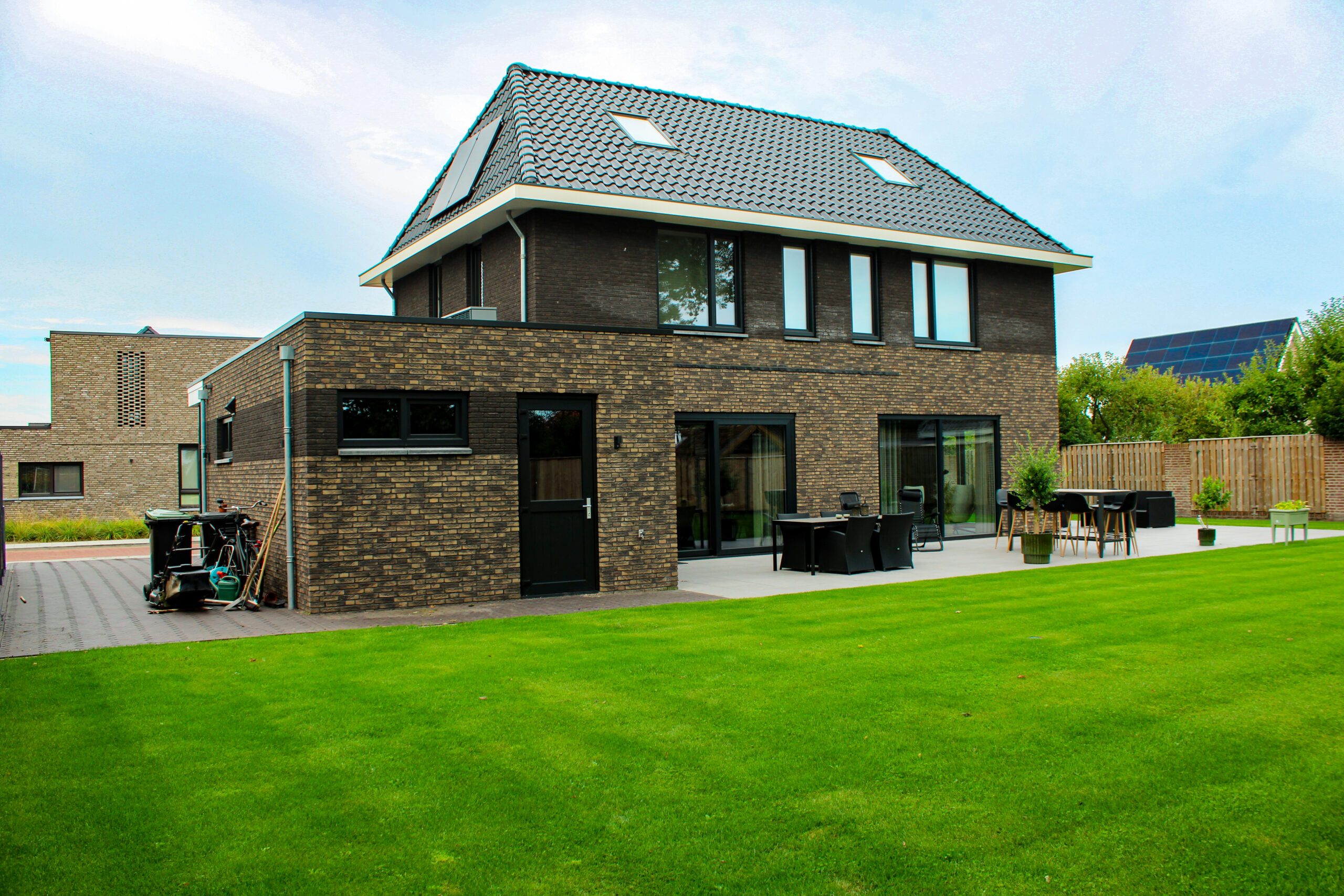 Achterzijde van vrijstaande nieuwbouwwoning met terras, tuin en grote raampartijen