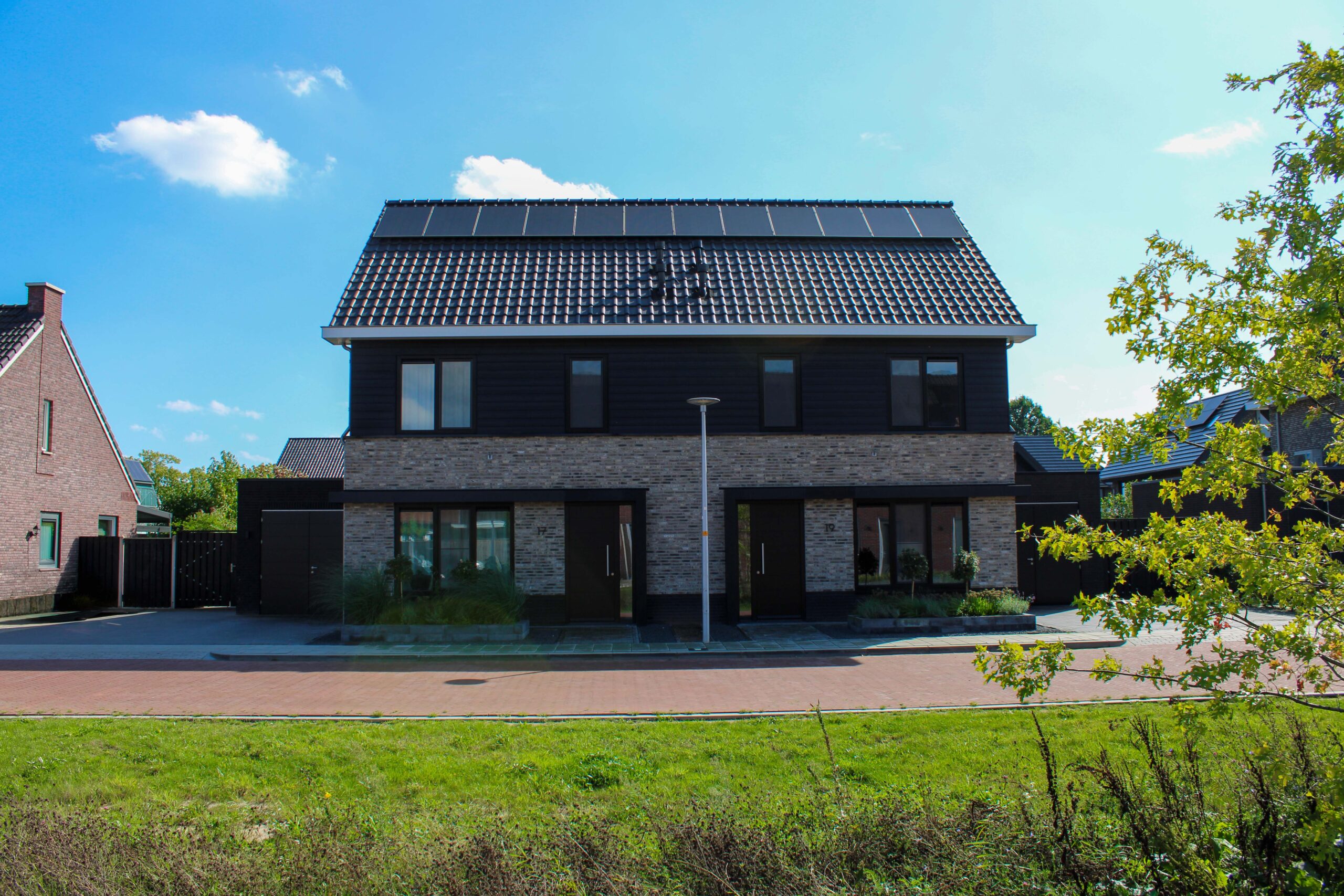 Twee-onder-een-kapwoningen aan de Snakenborg in Hengevelde met bakstenen gevel, donkere houten gevelbekleding en zonnepanelen