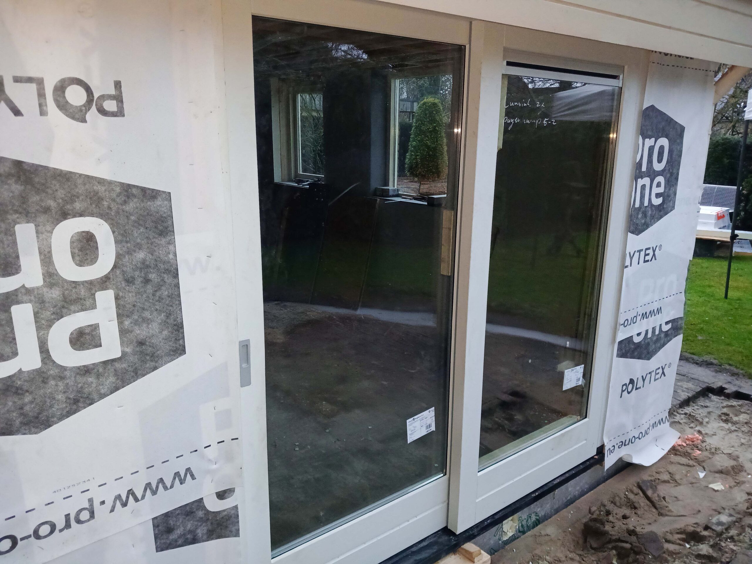 Nieuwe witte schuifpui met grote glaspartijen tijdens de verbouwing van een woning in Eibergen