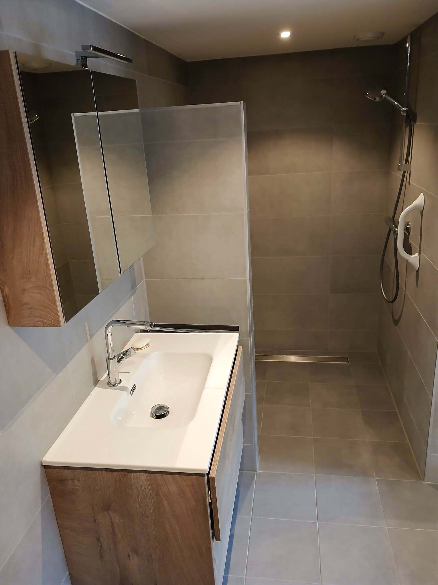 Moderne badkamer met grijze tegels, glazen douchewand en houten wastafelmeubel