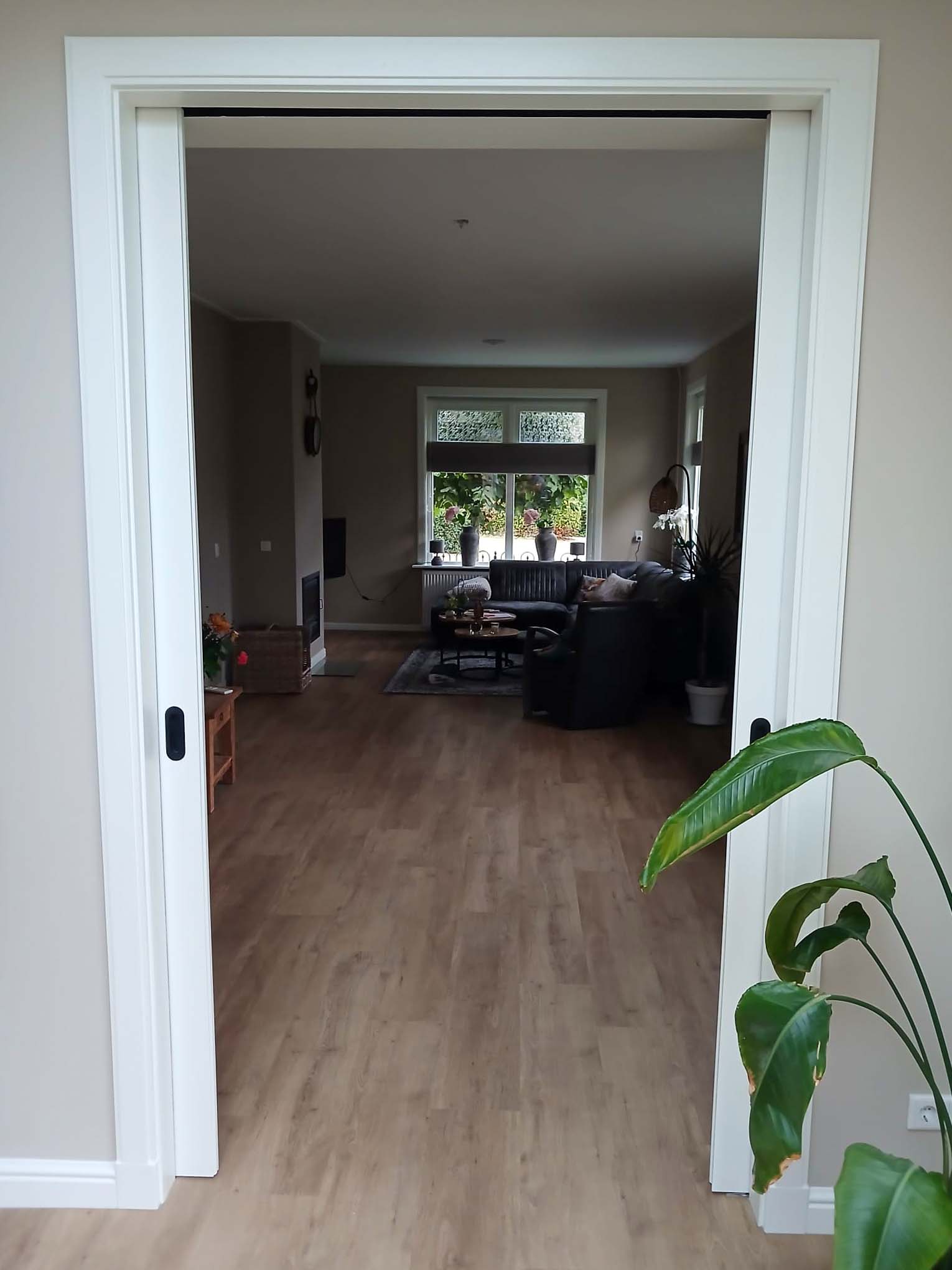 Doorkijk naar de woonkamer via een brede doorgang met witte omlijsting