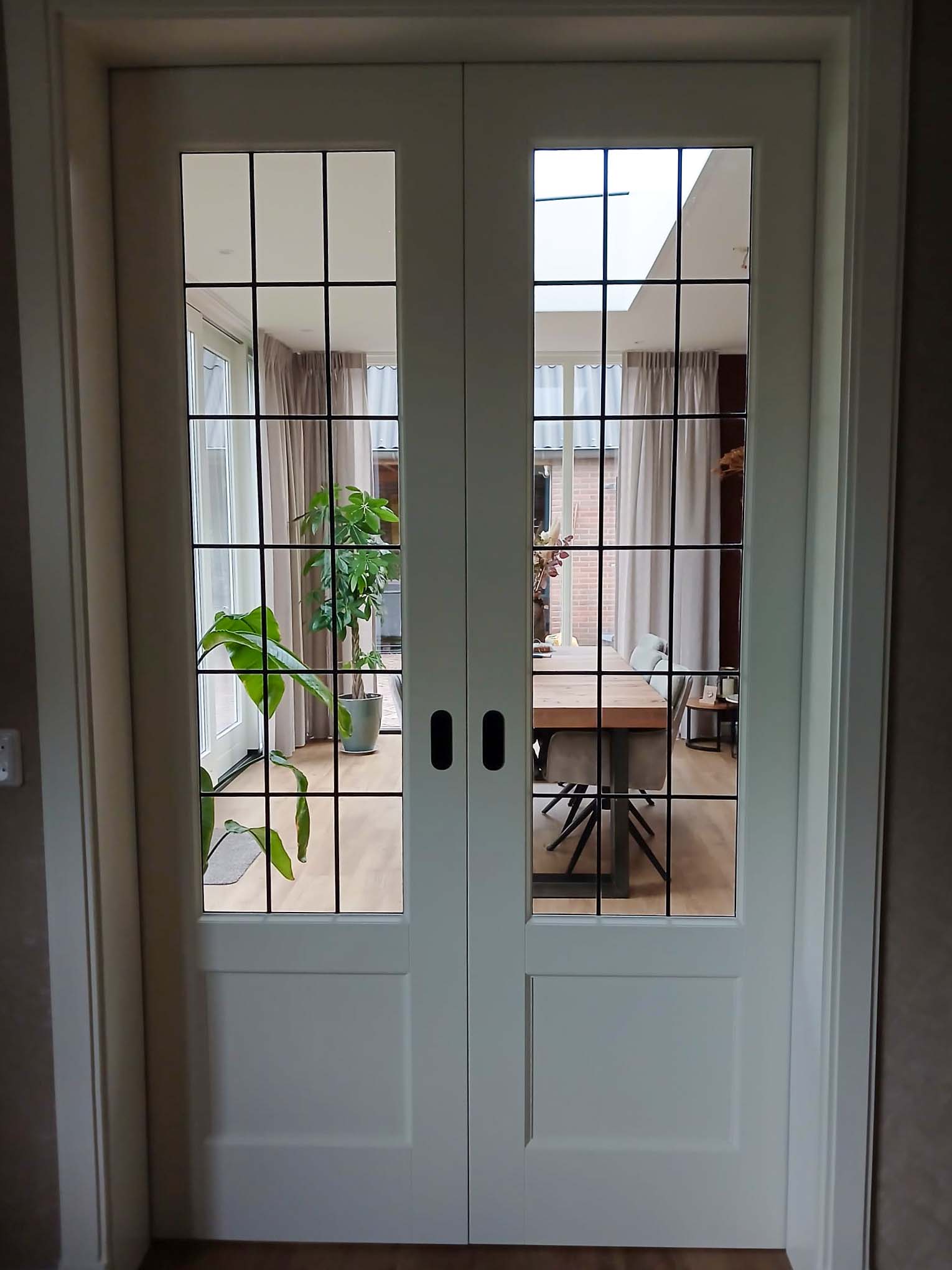 Witte dubbele schuifdeuren met glas tussen de eetkamer en woonkamer