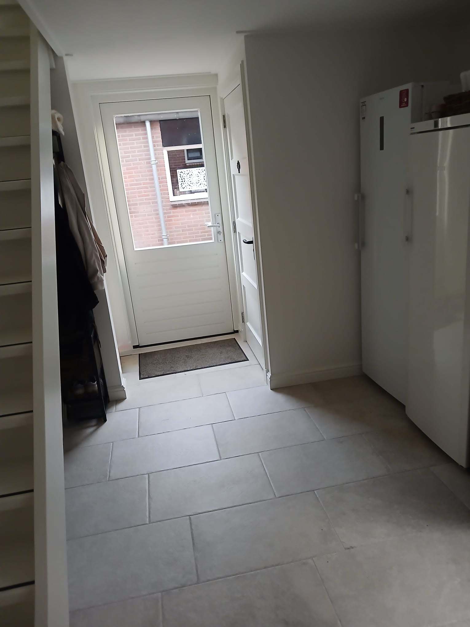 Hal met nieuwe tegelvloer, entree en garderobekast in Neede