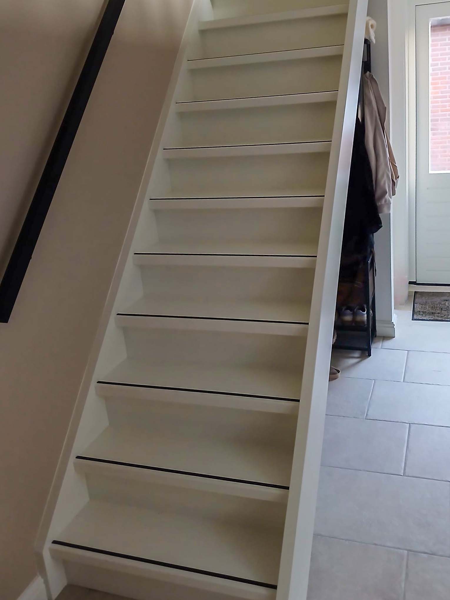 Witte trap met open opbergruimte in de hal van een woning in Neede